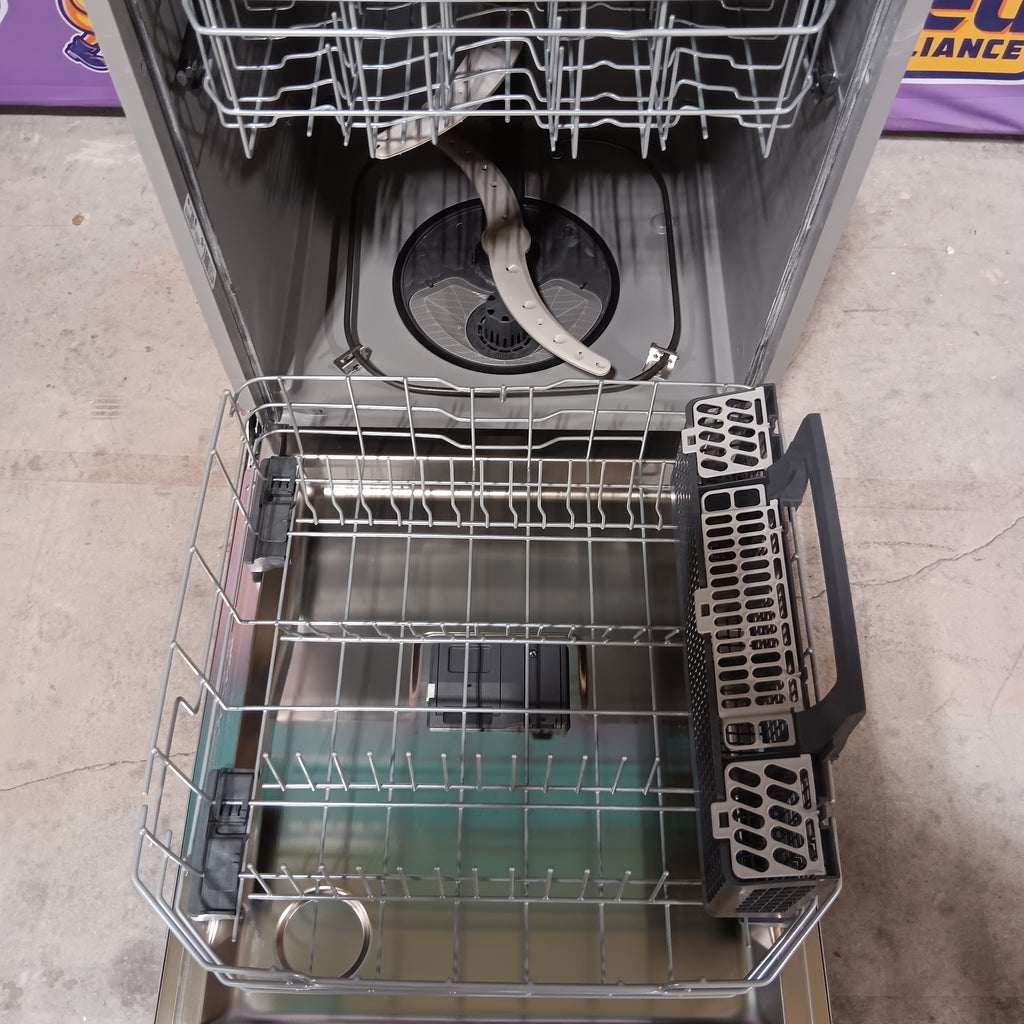 GE GDT565HSYSS Open dishwasher with racks and compartments on a concrete floor.
