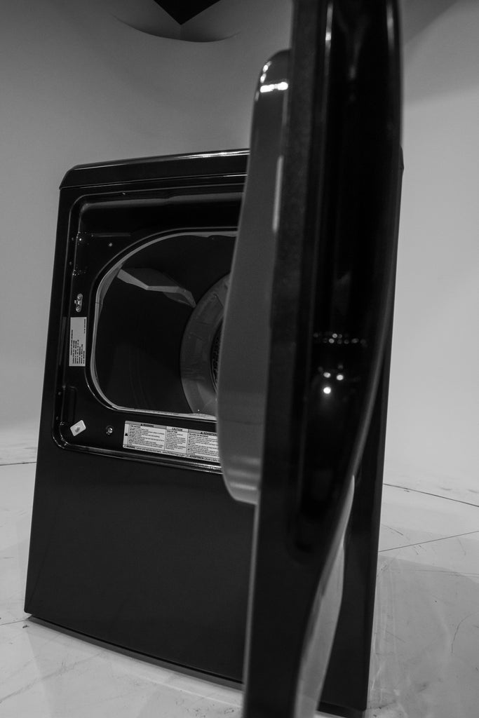 GE PTD60EBPRDG Black dryer with open door on a tiled floor