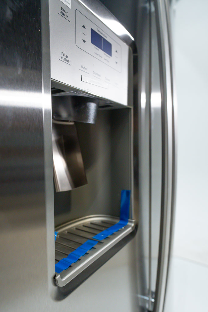 GE GSS25IYN Stainless steel refrigerator with water and ice dispenser, showing blue tape on the dispenser.