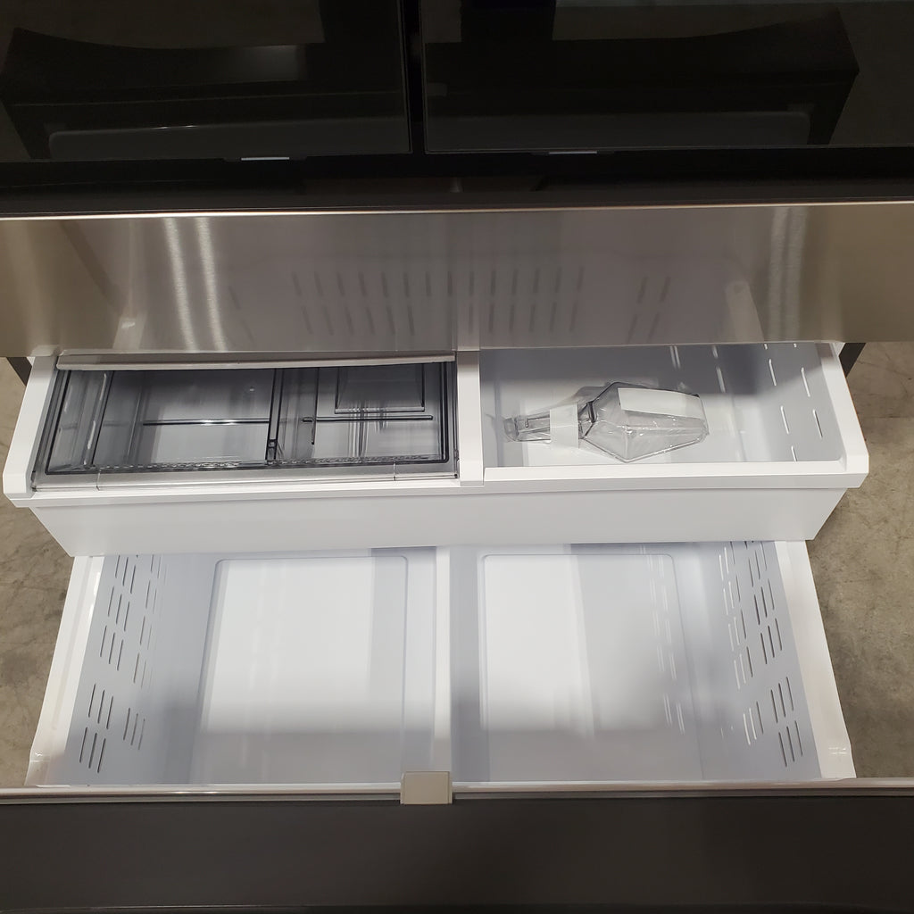 Open Samsung Bespoke RF90F29AECRAA 4-Door French Door Refrigerator with glass shelves and ice maker on a tiled floor.