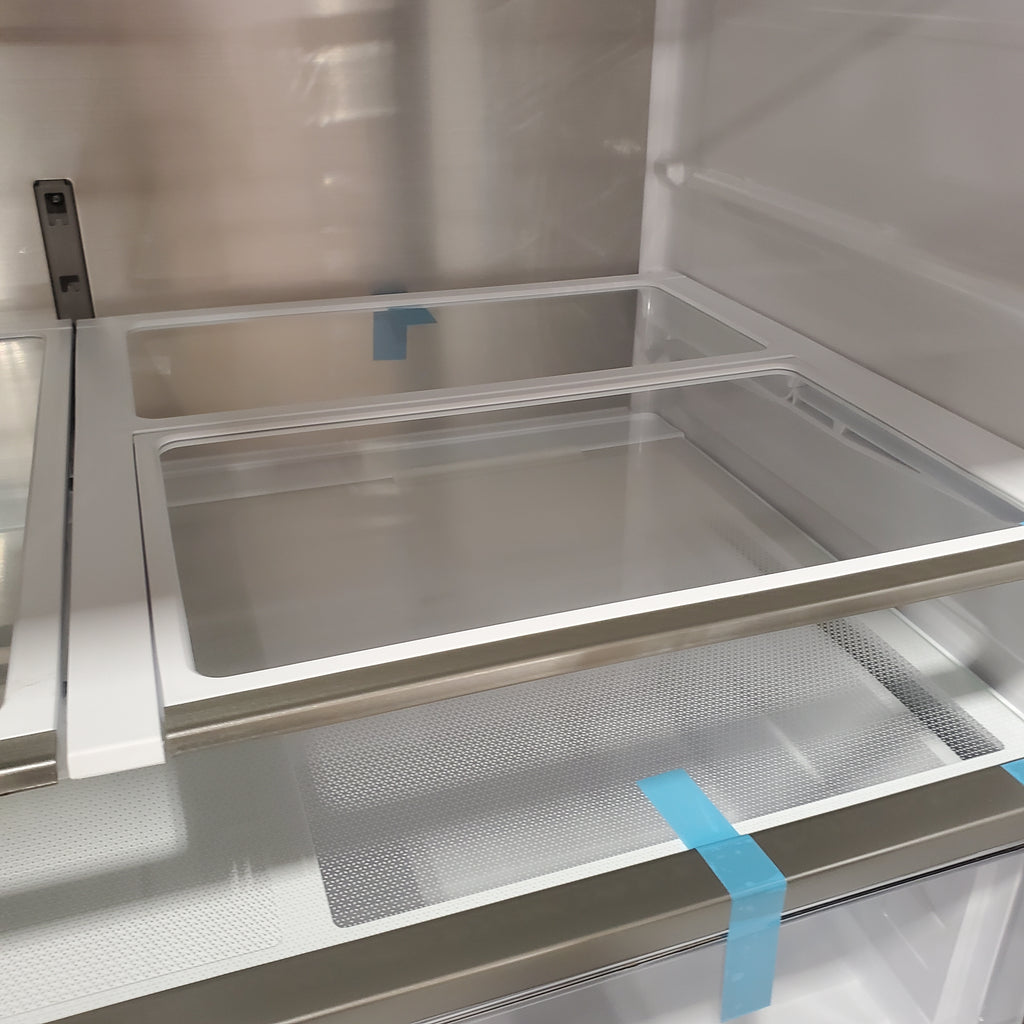 Glass door with blue tape on a Samsung Bespoke RF90F29AECRAA 4-Door French Door Refrigerator 