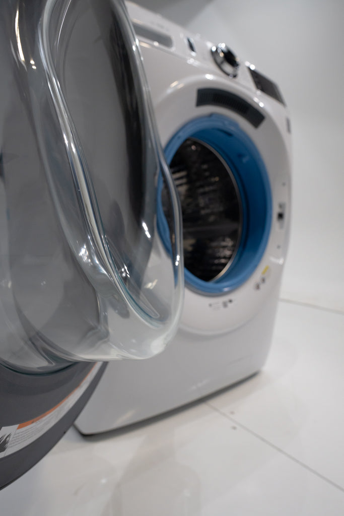 GE GFW550SSNWW White washing machine with open door on a white floor